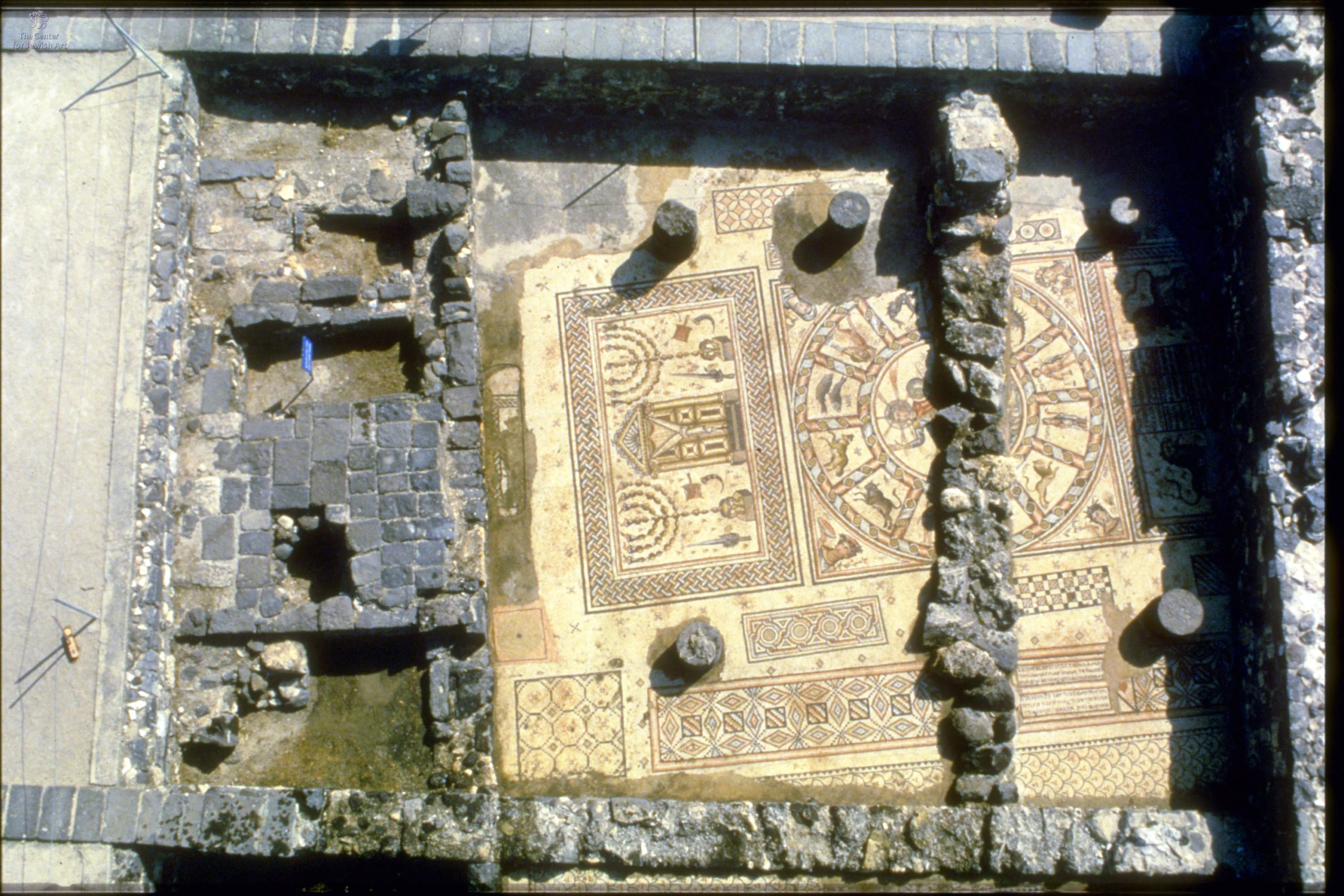 The mosaic floor of the ancient synagogue at Hammath Tiberias, showing a central zodiac wheel and a panel with a Torah ark flanked by menorahs.
