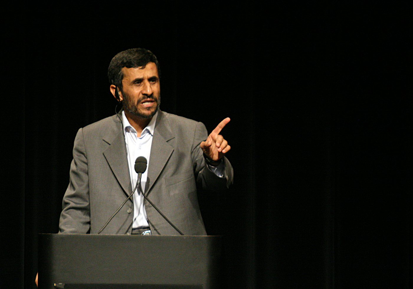 Mahmoud Ahmadinejad gestures with a raised finger from a dark podium at Columbia University.