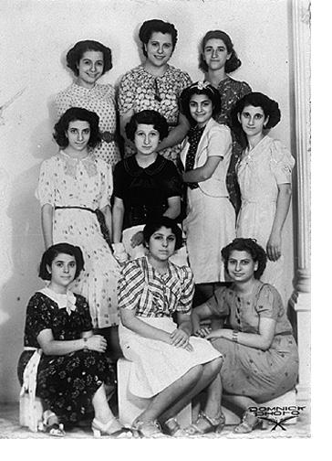 A 1939 studio portrait of nine young women in patterned dresses, students at the Alliance Israélite school for girls in Basra, Iraq.