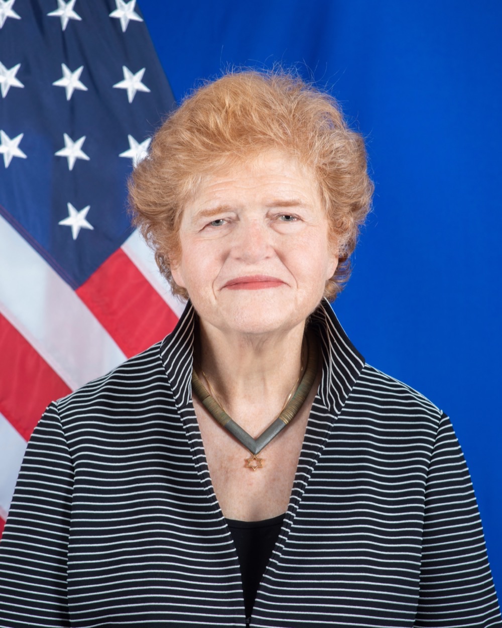An official portrait of the historian Deborah Lipstadt against a United States flag and blue backdrop.