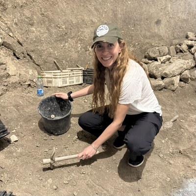 Orit Yakuel at an active archaeological excavation, holding a small pick, during the Dig for a Day program at Beit Guvrin-Maresha, Israel