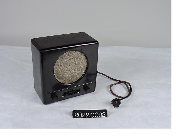 A 1930s German Volksempfänger radio receiver: a black bakelite set with a circular cloth-covered speaker and a power cord.