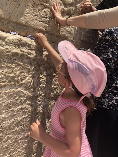 A young child placing a note in the Western Wall in Jerusalem