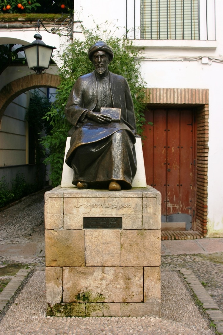 A bronze statue of a seated, turbaned Maimonides holding a book, on a stone pedestal in a square in Córdoba's old Jewish quarter.