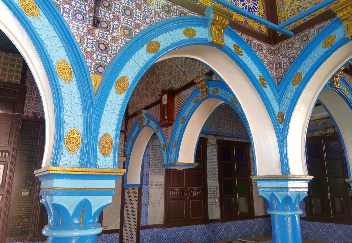The brightly painted blue-and-gold tiled interior arches of the El Ghriba synagogue in Djerba, Tunisia.