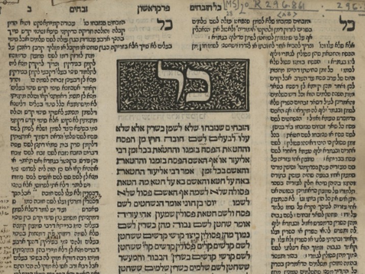 A printed Talmud page: a block of text in the center under a decorated initial-word panel, flanked by two columns of smaller commentary type on the inner and outer margins.