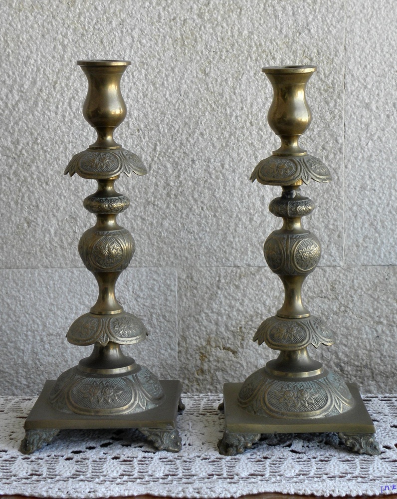 A pair of brass Sabbath candlesticks on a lace cloth