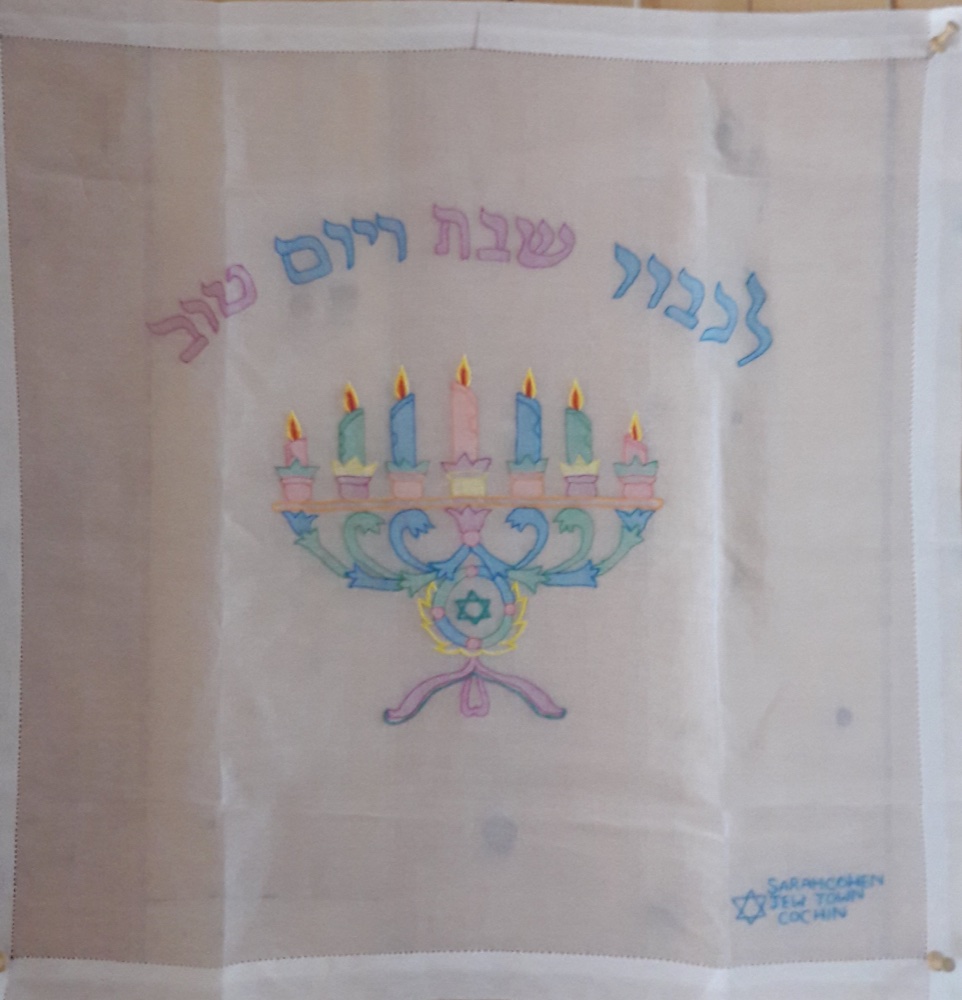 A hand-painted challah cover from Cochin, India, with a candelabrum and Hebrew lettering