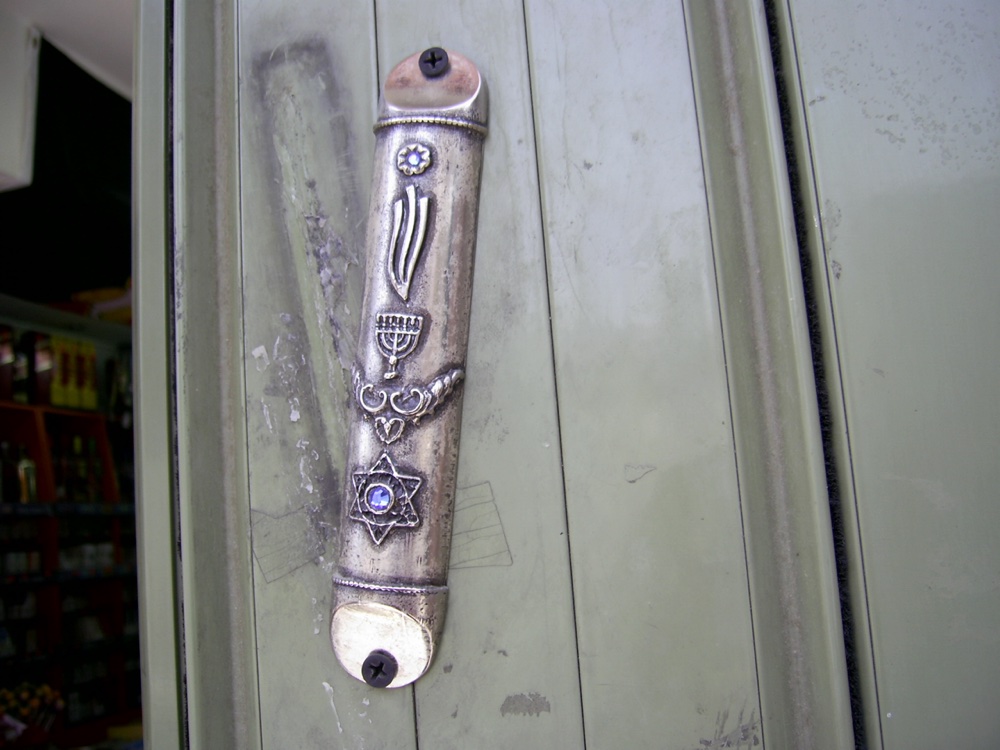 A silver mezuzah case fixed to a doorpost