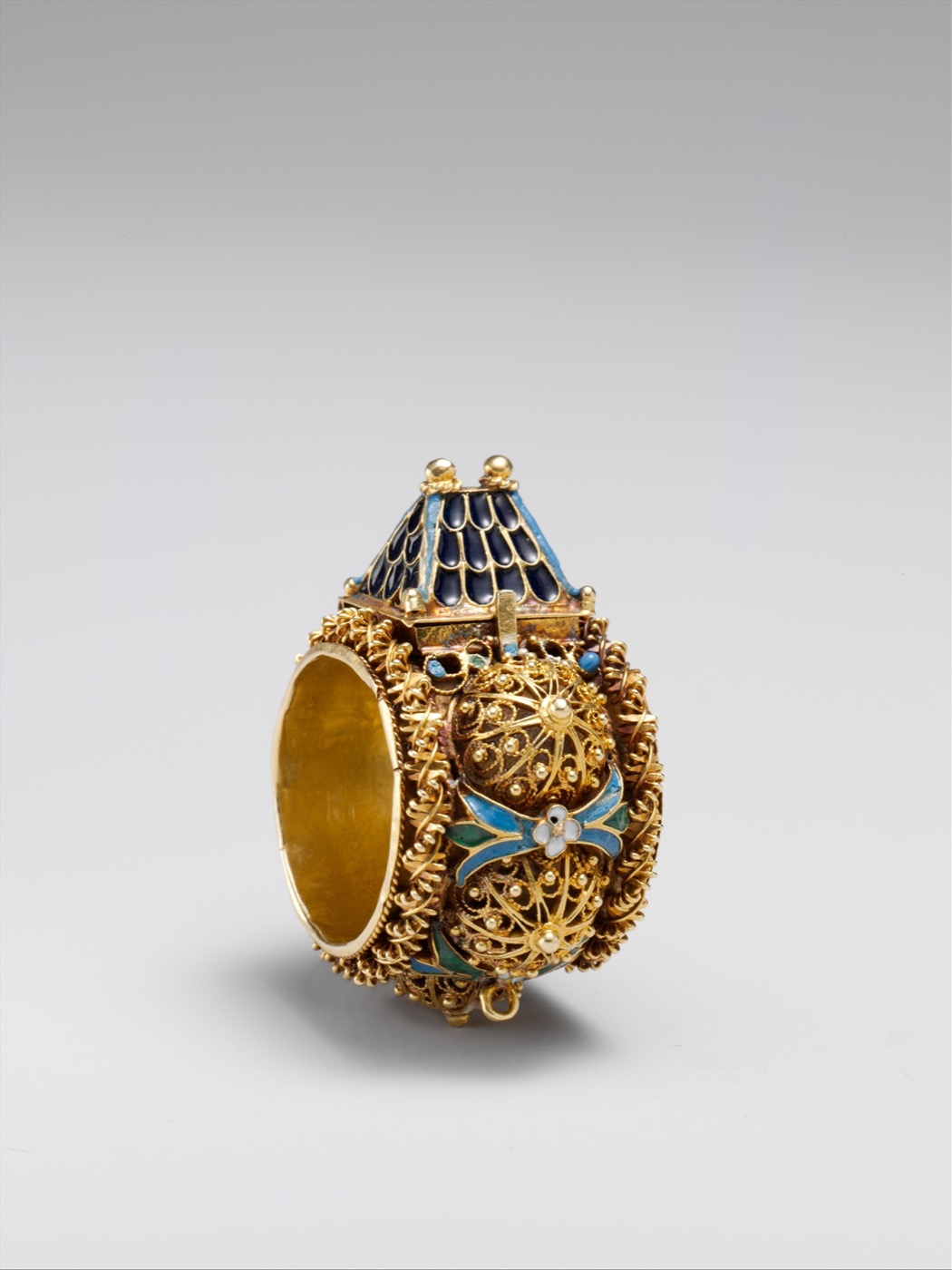 A gold Jewish ceremonial wedding ring topped with a hinged miniature house with a blue enamel roof