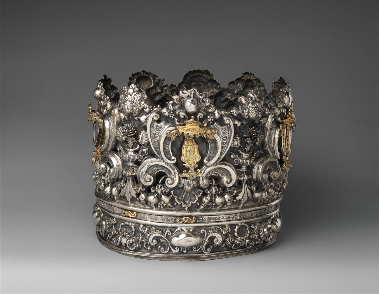 A silver Torah crown hung with bells, made to sit over the top of a Torah scroll