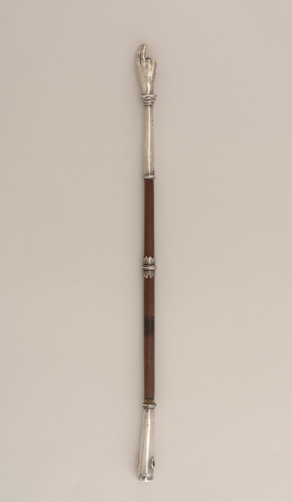 A silver and wood Torah pointer ending in a small pointing hand