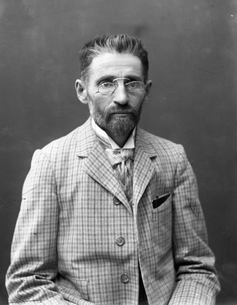 A formal early-twentieth-century portrait of Eliezer Ben-Yehuda, bearded, in a dark suit.